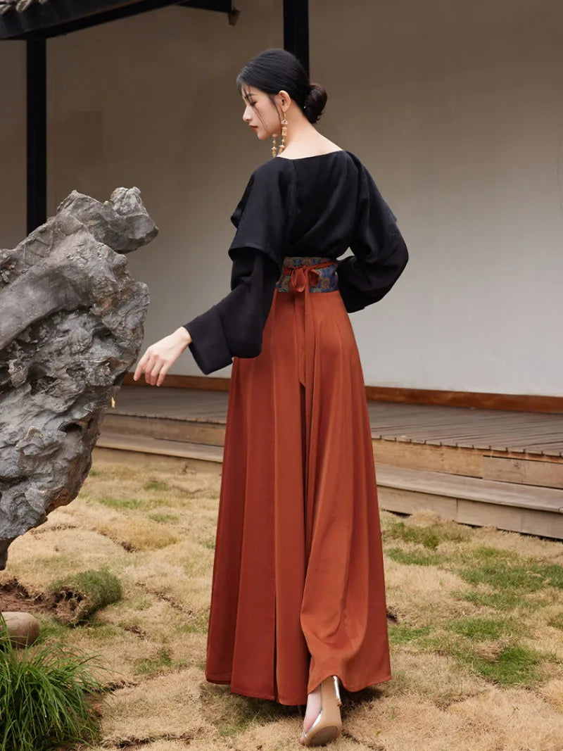 Model holding out the rust-orange hanfu skirt to show its wide flowing panels