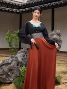 Model holding out the rust-orange hanfu skirt to show its wide flowing panels