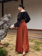 Model holding out the rust-orange hanfu skirt to show its wide flowing panels