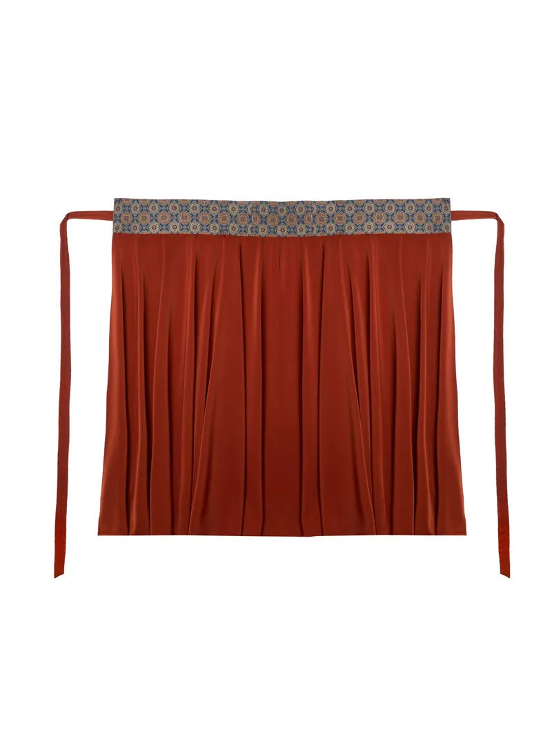 Model holding out the rust-orange hanfu skirt to show its wide flowing panels